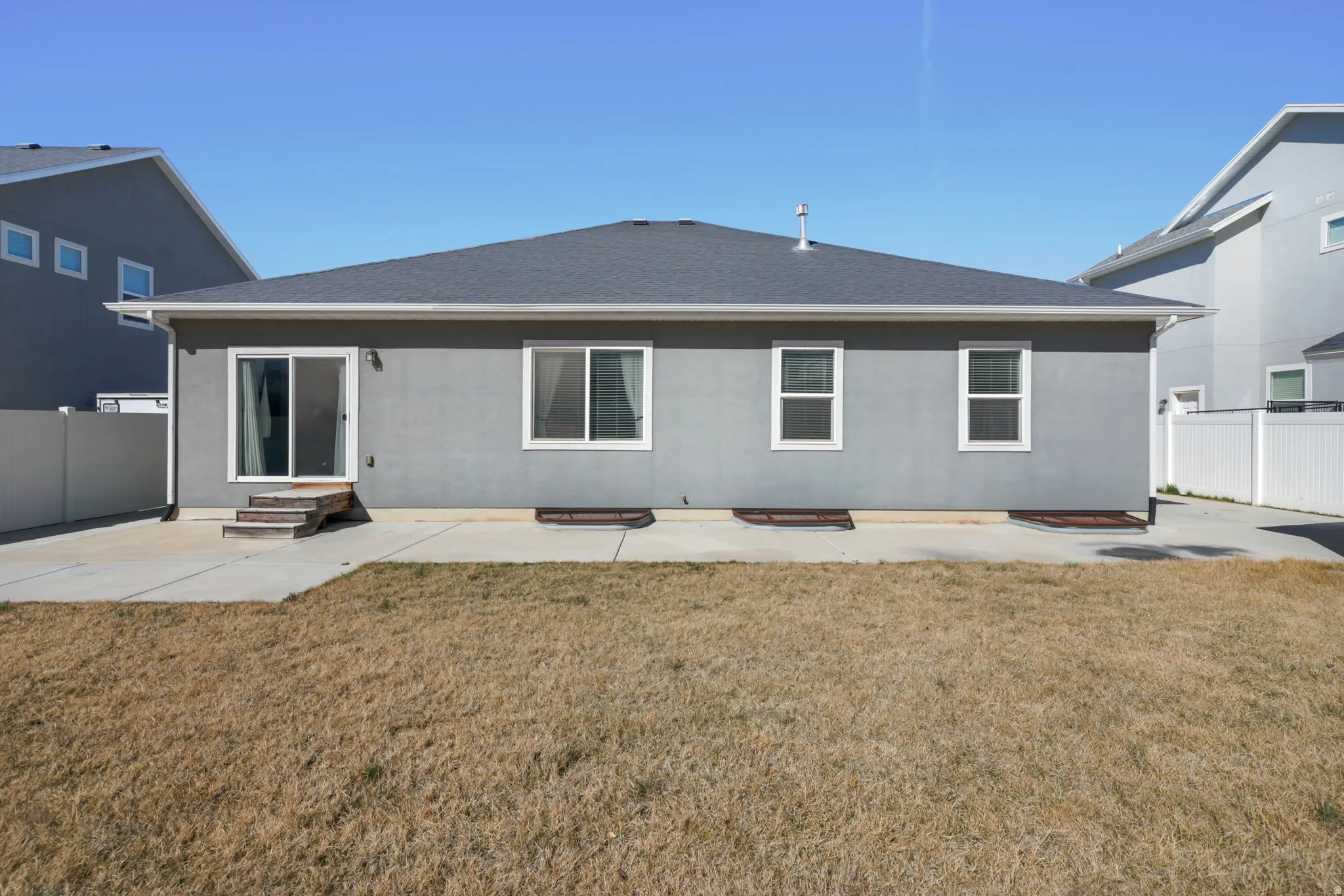 Back of house featuring a patio area, stucco siding, and a shingled roof