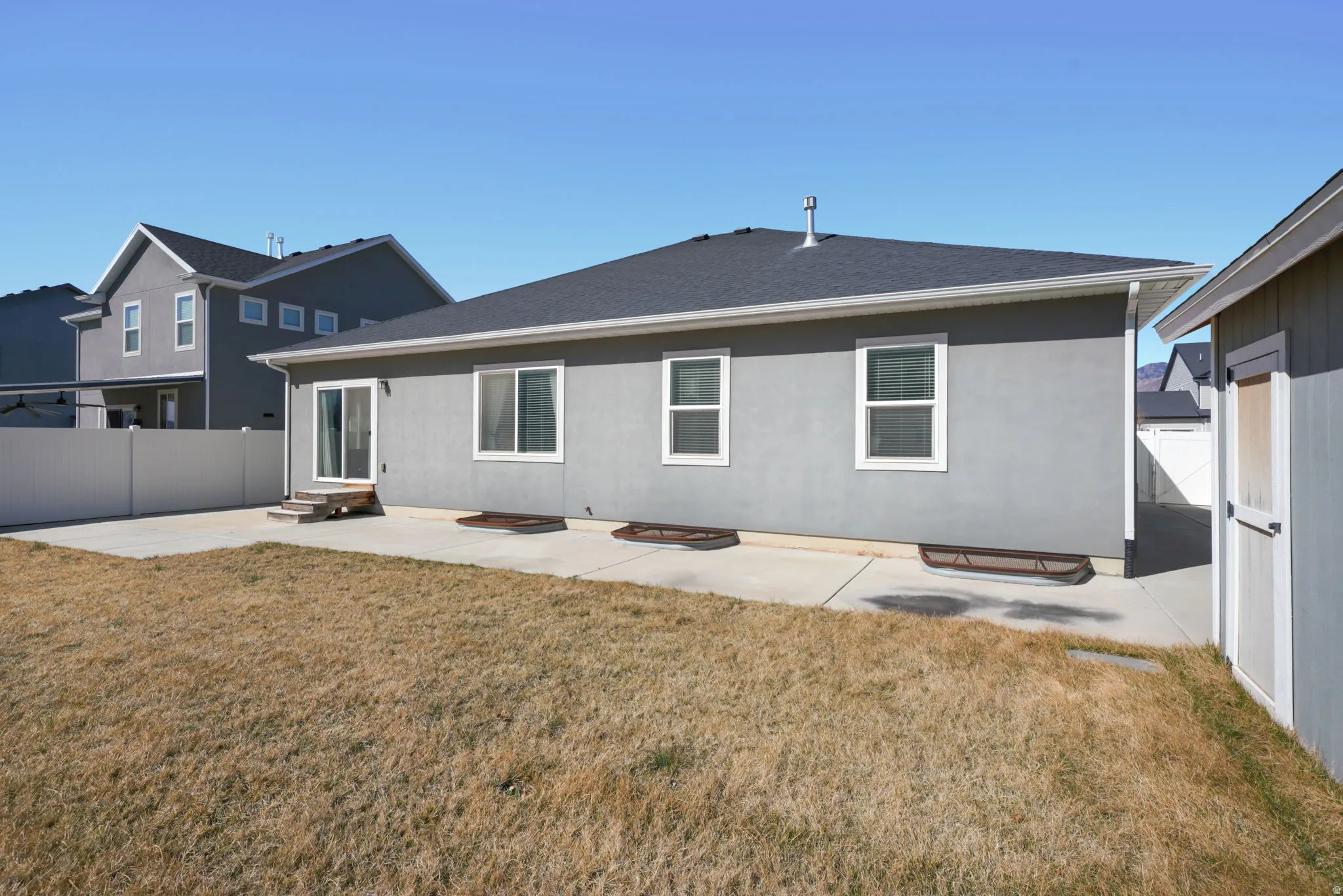 Rear view of property featuring a patio area, roof with shingles, and stucco siding