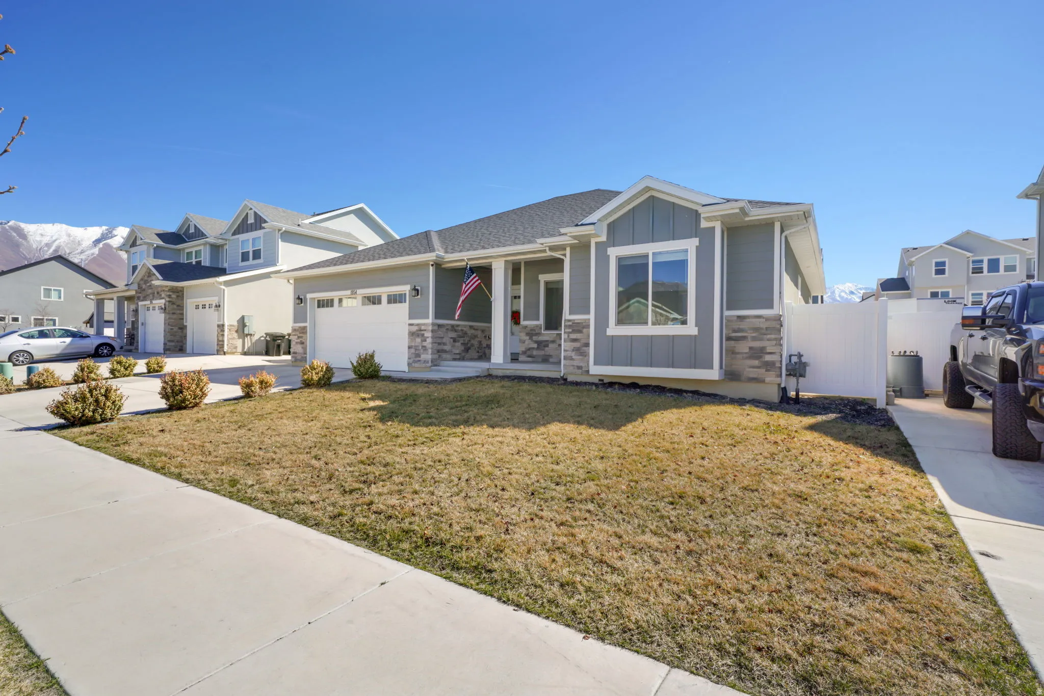View of front facade featuring board and batten siding, stone siding, a residential view, and concrete driveway