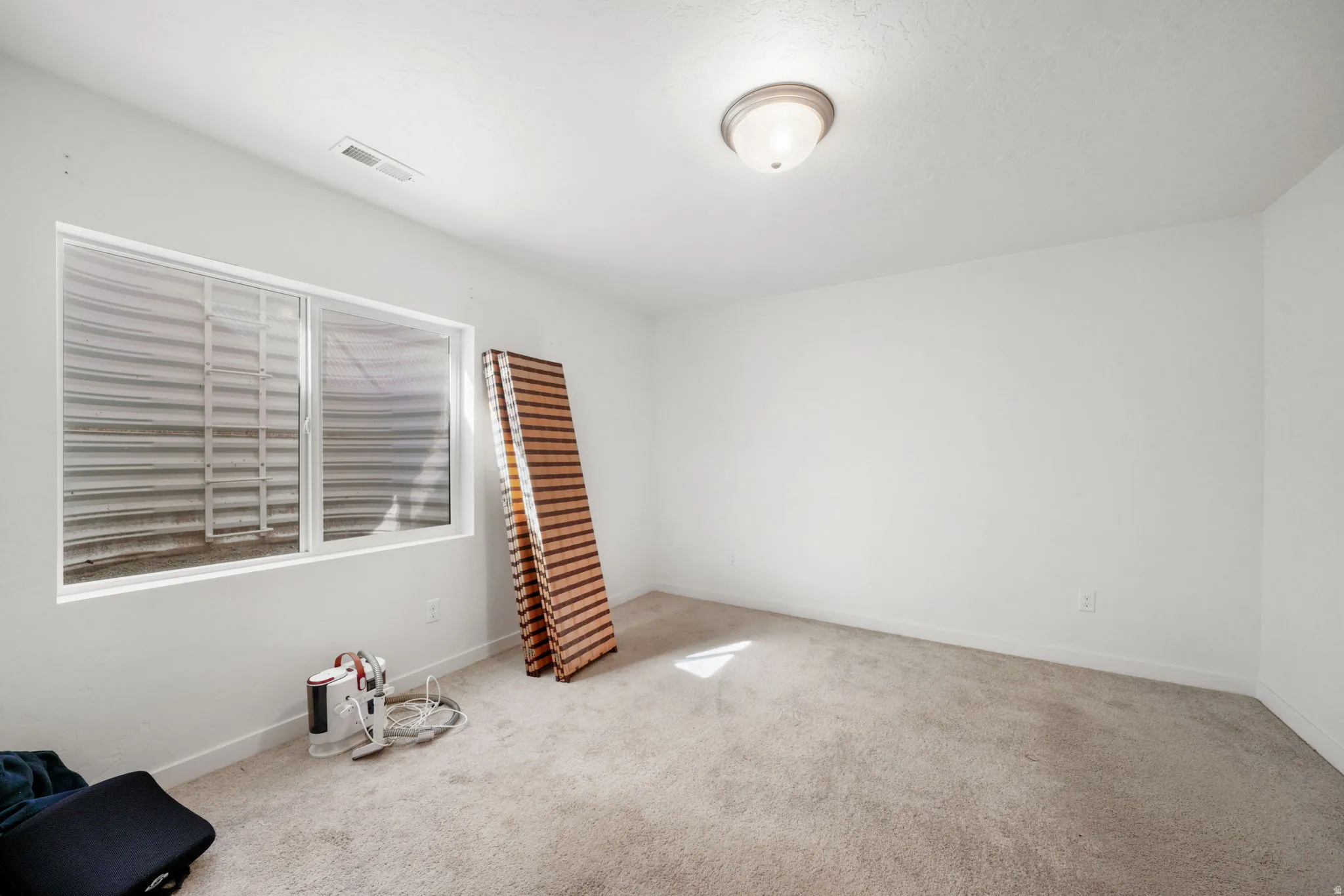 Empty room featuring light colored carpet and baseboards
