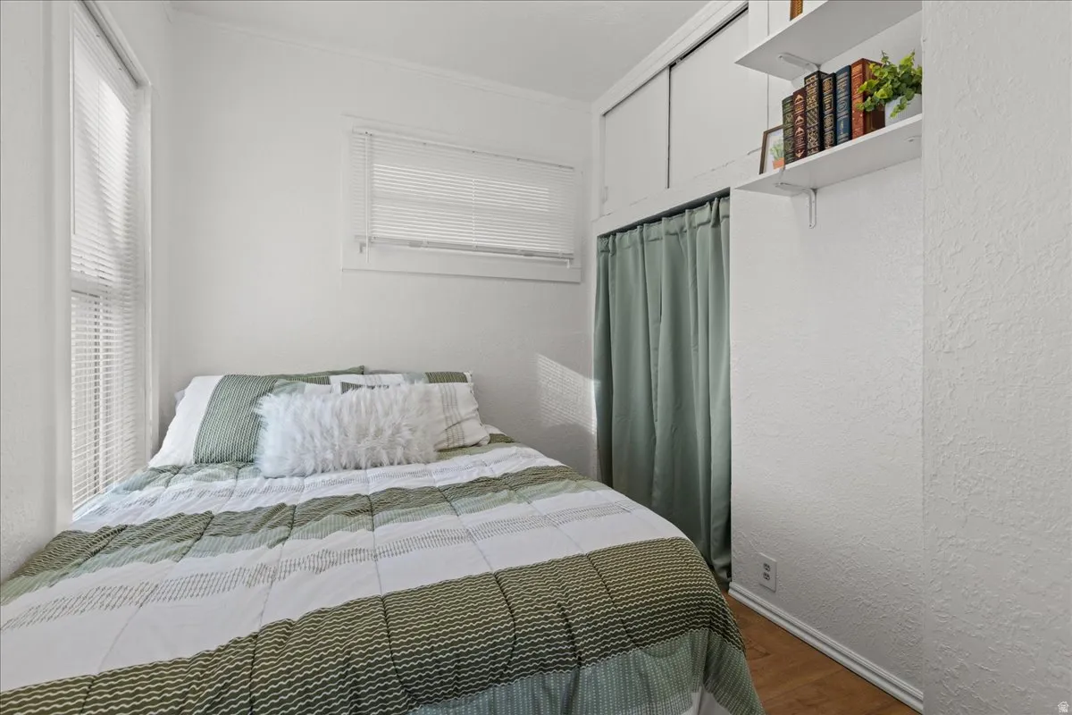 Bedroom featuring wood finished floors, a textured wall, and ornamental molding