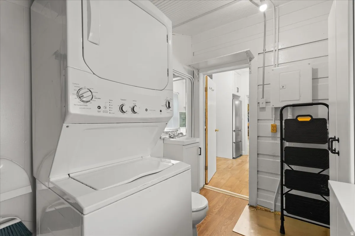 Laundry area featuring stacked washer and dryer and light wood-style floors