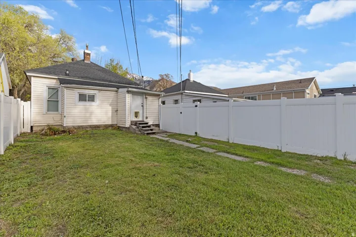 Back of property featuring a fenced backyard, entry steps, and a chimney
