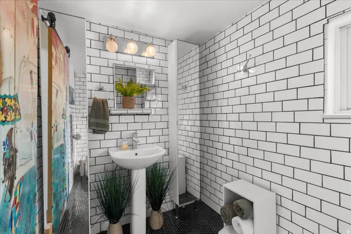Bathroom with tile walls, tile patterned floors, and a shower