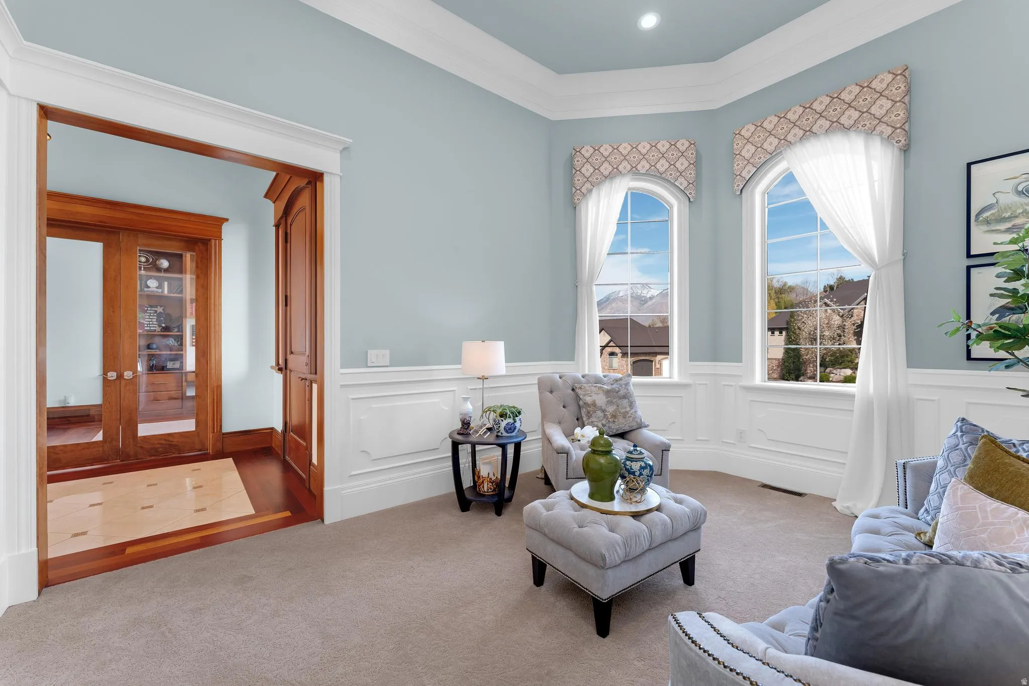 Living area with ornamental molding, carpet flooring, and wainscoting