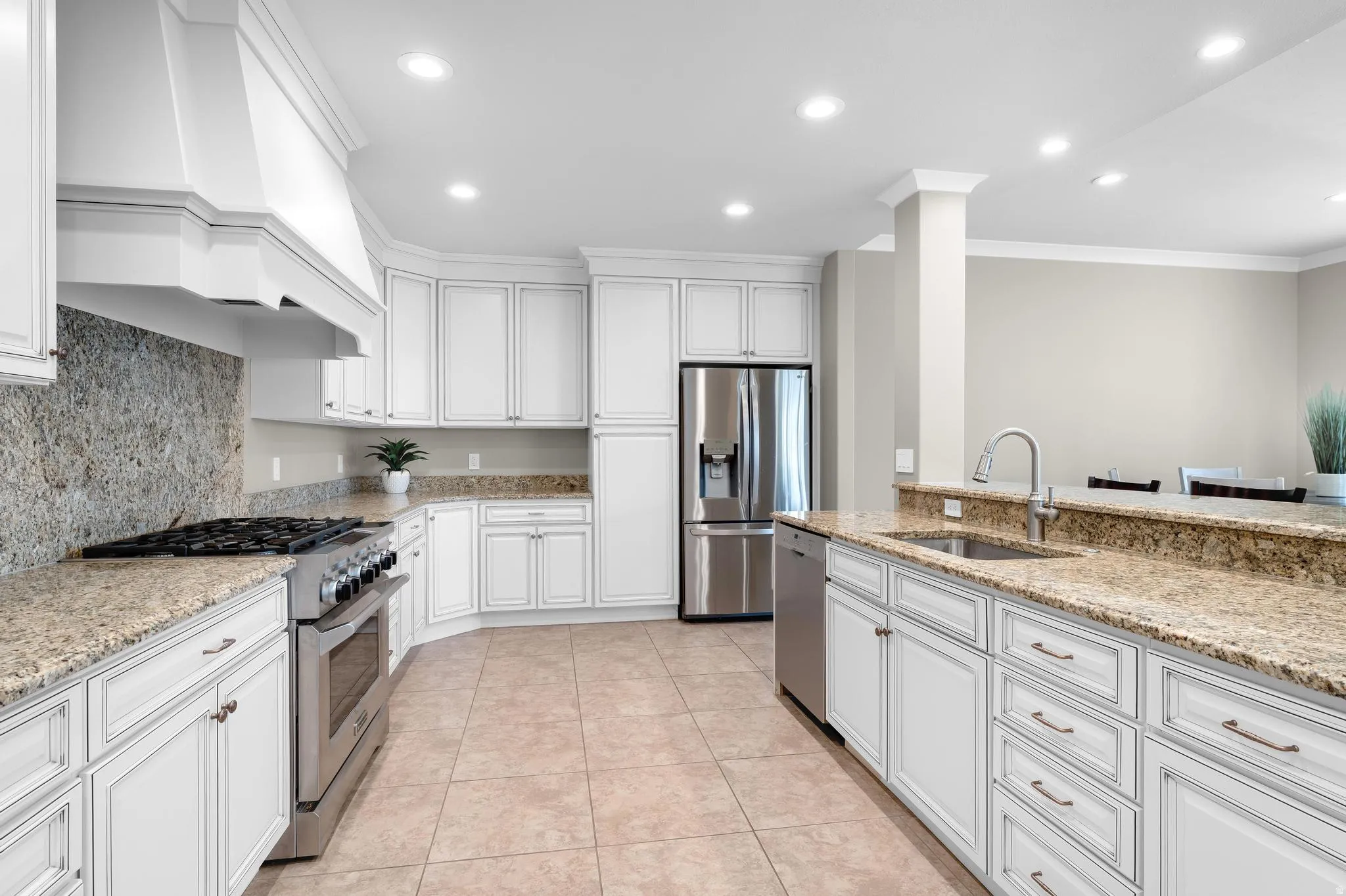 Kitchen featuring stainless steel appliances, white cabinets, ornamental molding, recessed lighting, and light stone counters
