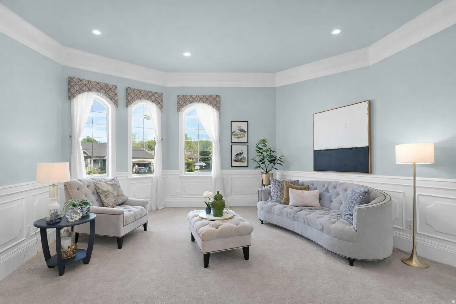 Carpeted living area with a wainscoted wall, ornamental molding, and a decorative wall