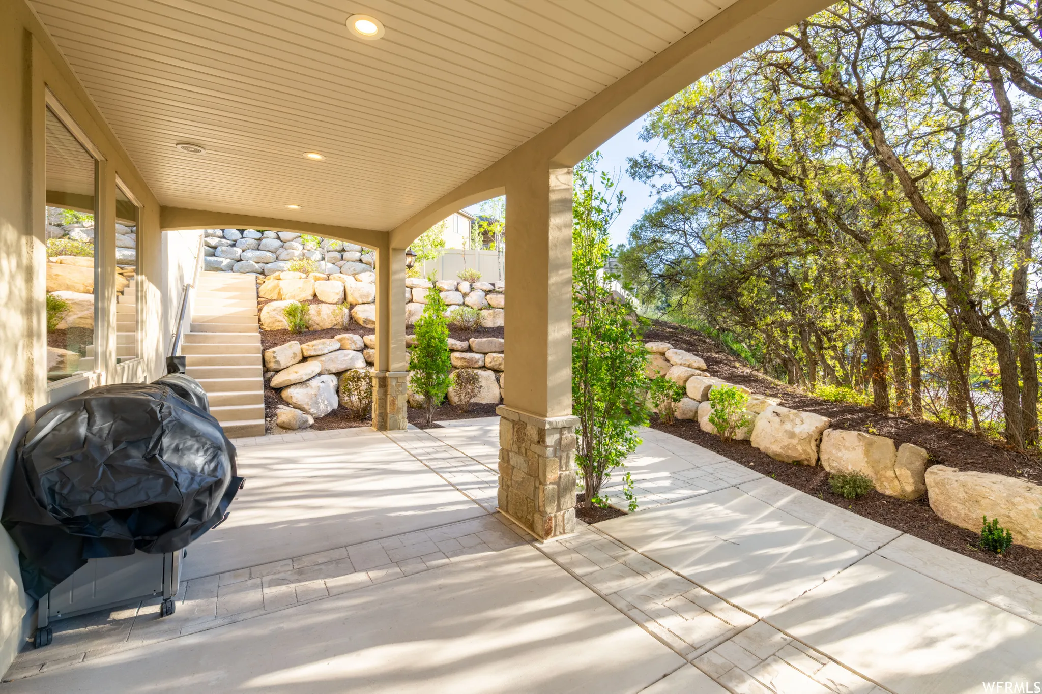 Covered patio featuring an arched entryway, recessed lighting, and a stone-clad support column