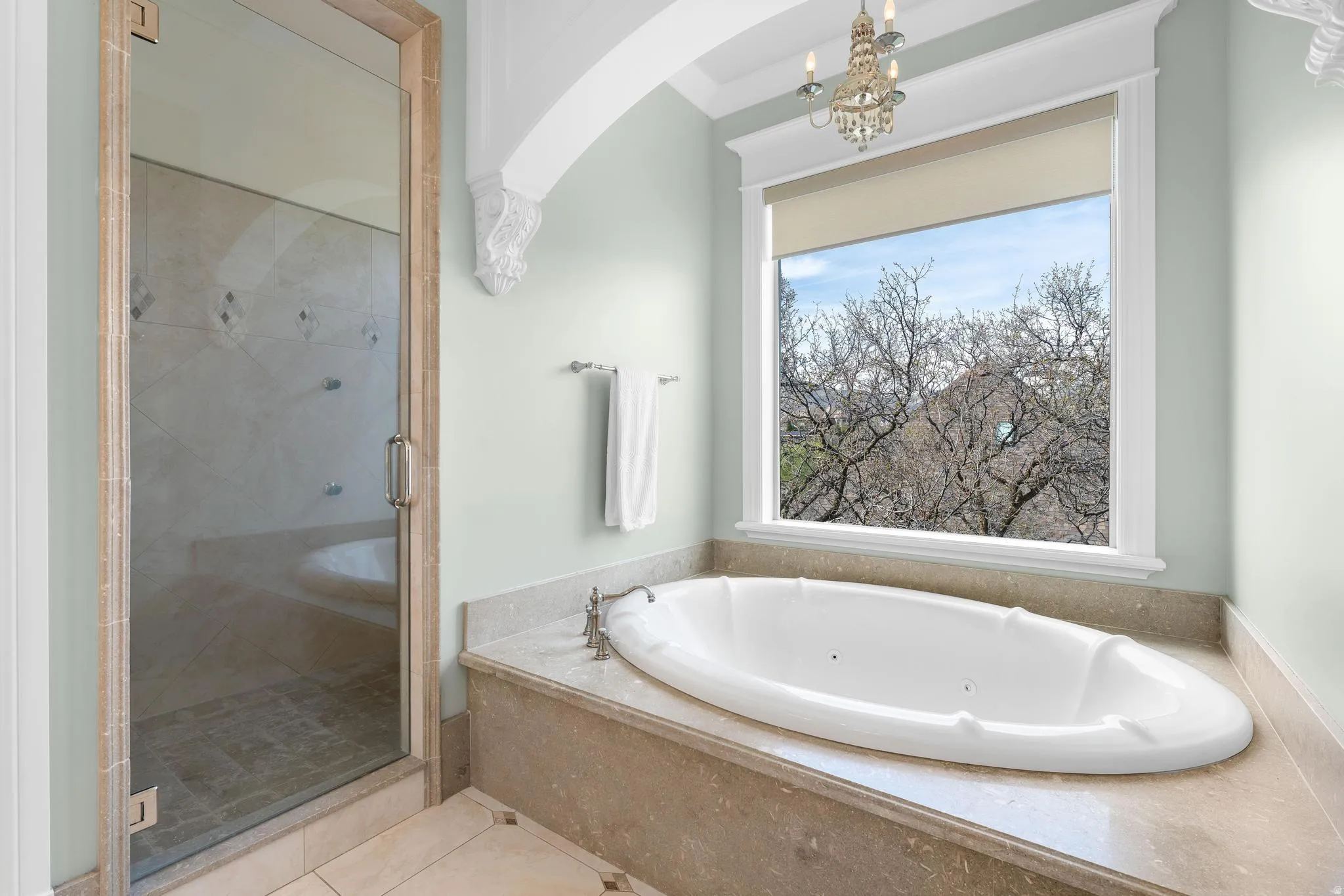 Bathroom featuring a tub with jets, a stall shower, light tile patterned floors, and suspended lighting