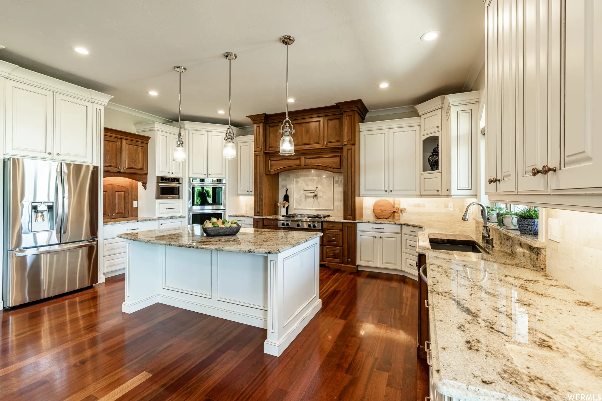 Kitchen featuring stainless steel appliances, light stone countertops, backsplash, dark wood finished floors, and ornamental molding