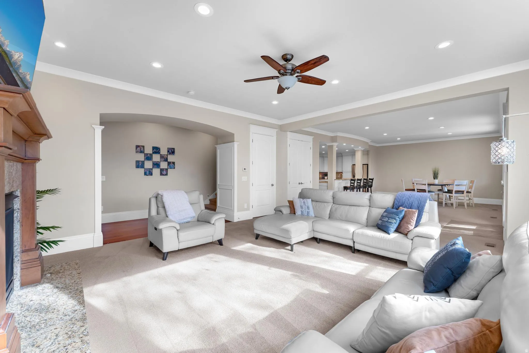 Living area featuring crown molding, ceiling fan, recessed lighting, a fireplace, and arched walkways