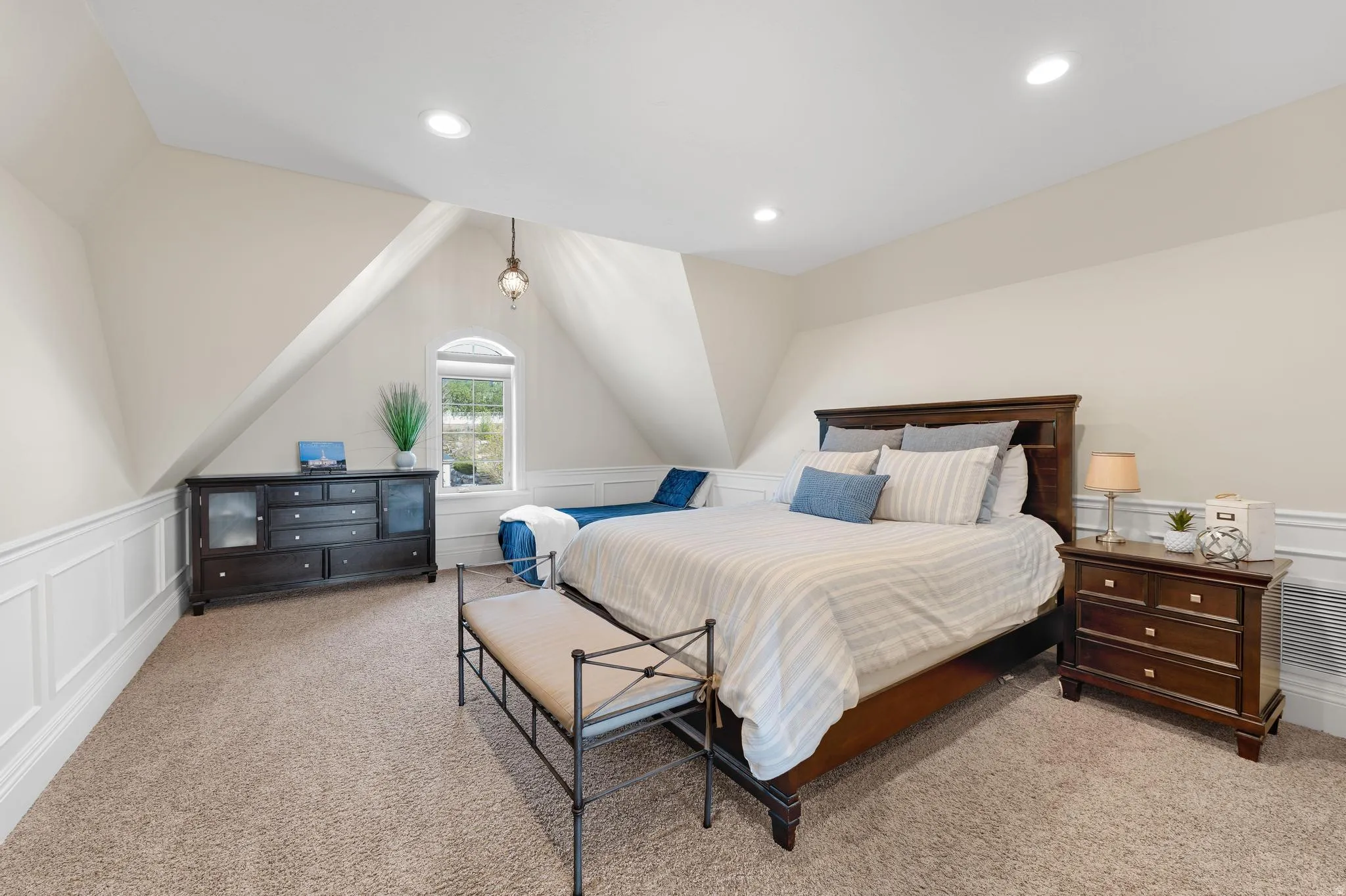 Bedroom with a decorative wall, wainscoting, light colored carpet, vaulted ceiling, and recessed lighting