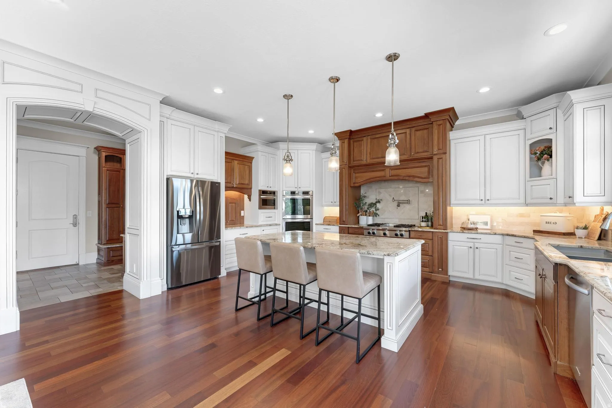 Kitchen with light stone counters, a center island, stainless steel appliances, arched walkways, and a breakfast bar