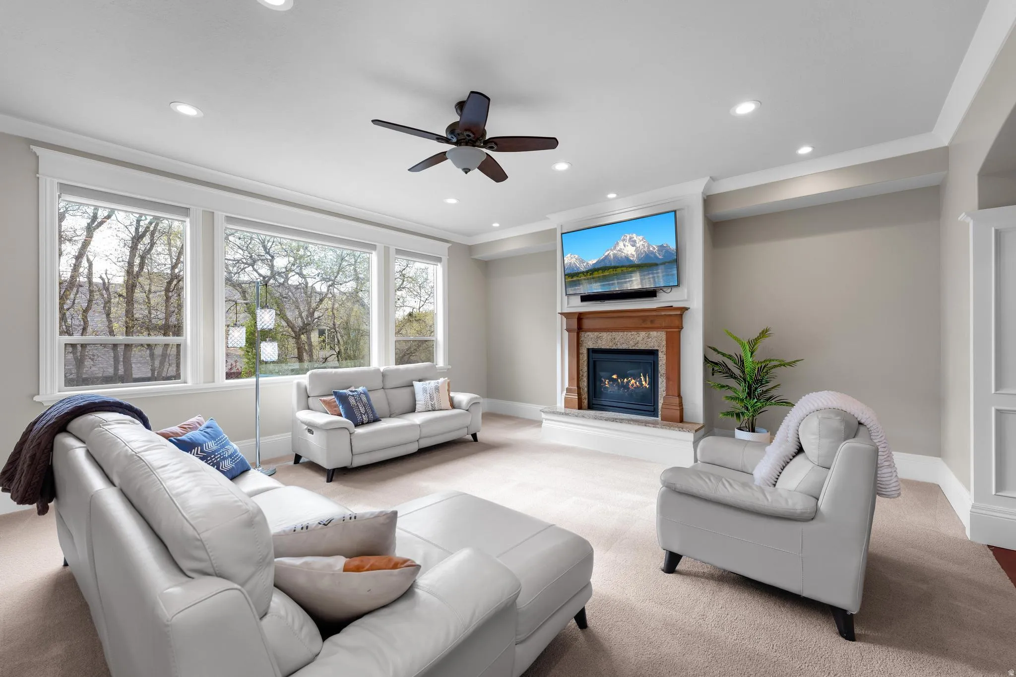 Carpeted living area with a ceiling fan, a glass covered fireplace, recessed lighting, and ornamental molding