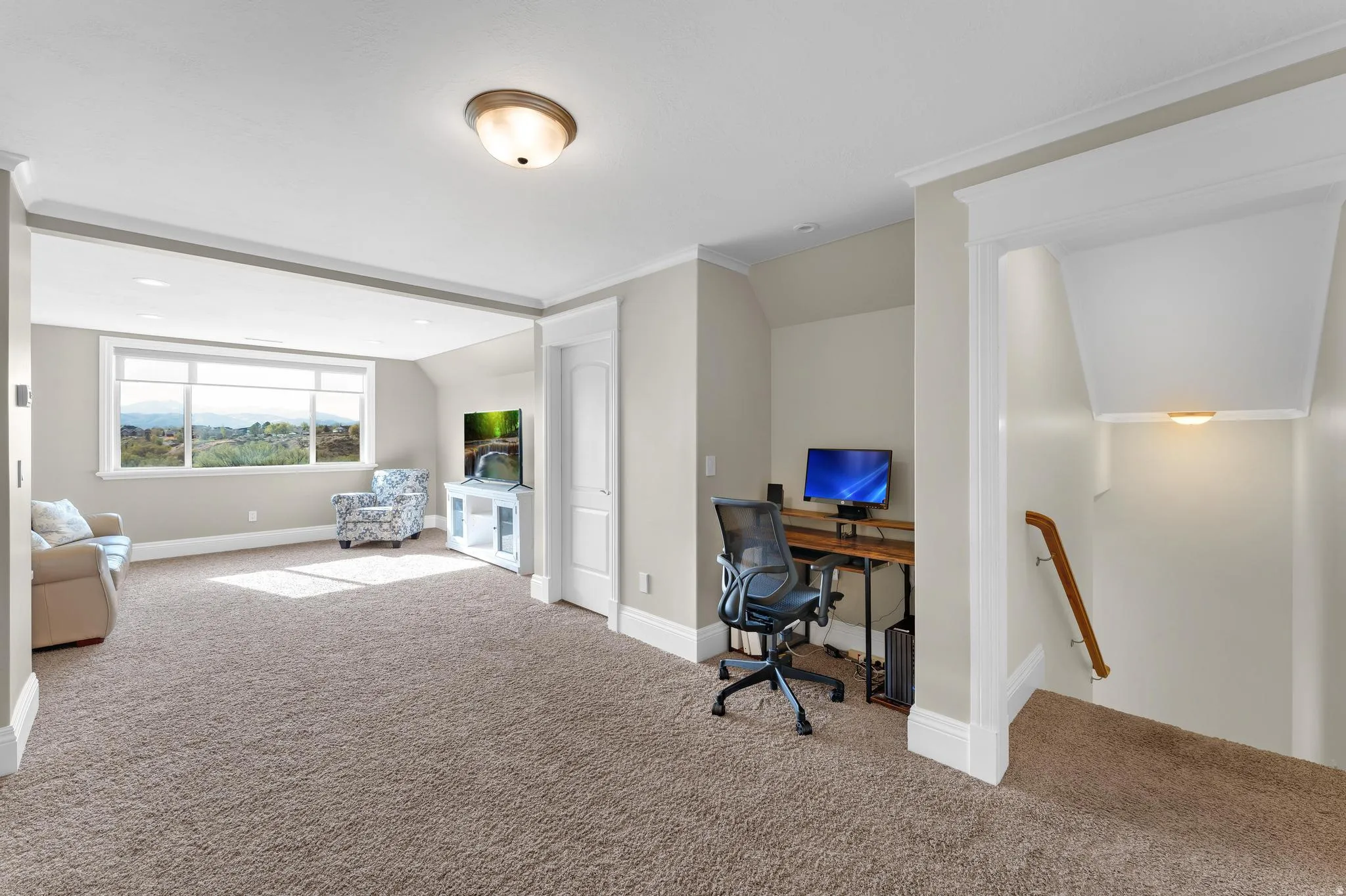 Home office with lofted ceiling, light carpet, and ornamental molding