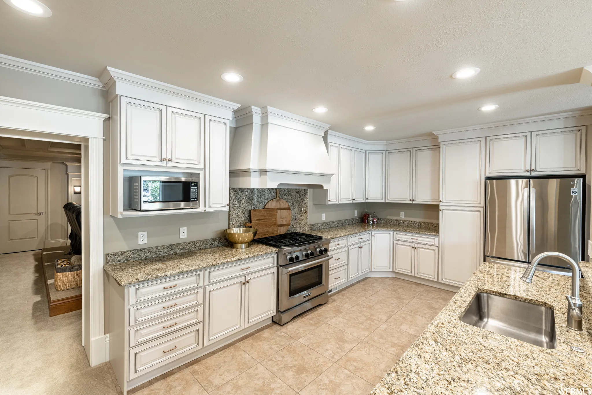 Kitchen featuring granite countertops, extensive white cabinetry, stainless steel appliances, a built-in microwave, and tile flooring