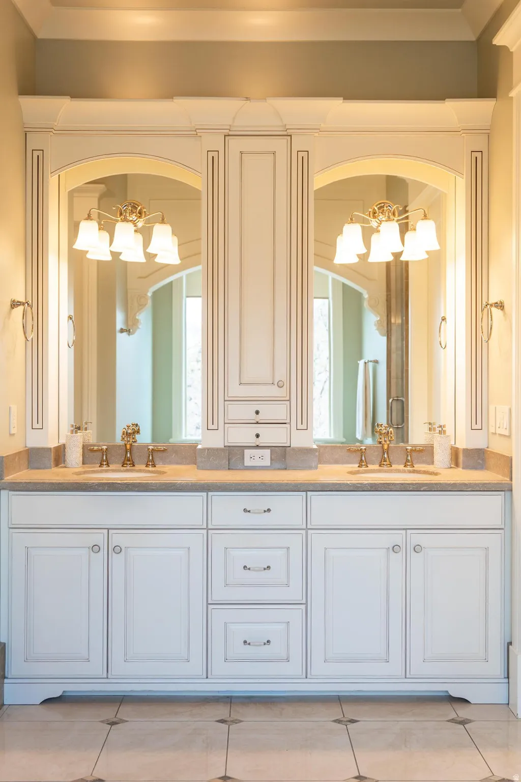 Full bath with double vanity, hanging lights, and light tile patterned flooring