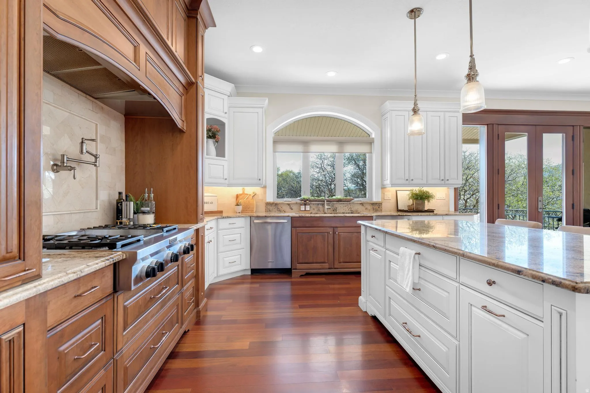 Dual tone kitchen with light stone countertops, decorative backsplash, dark wood-type flooring, stainless steel appliances, and two tone cabinetry