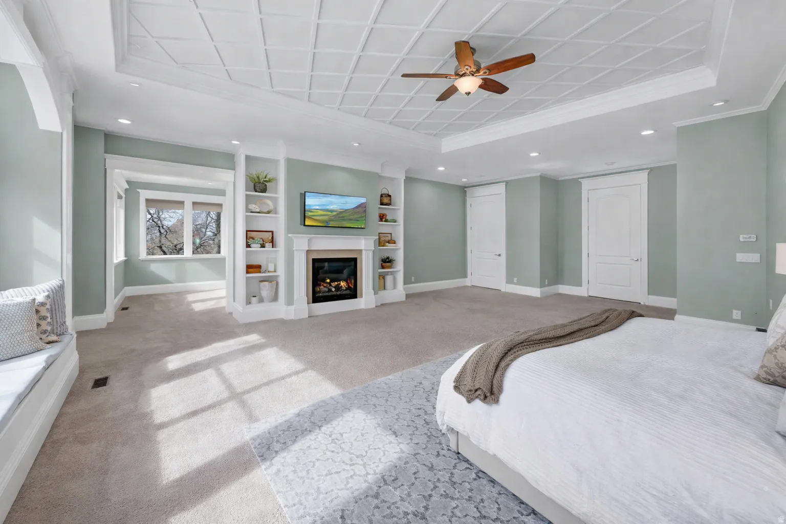 Bedroom featuring recessed lighting, a glass covered fireplace, carpet floors, a raised ceiling, and a ceiling fan