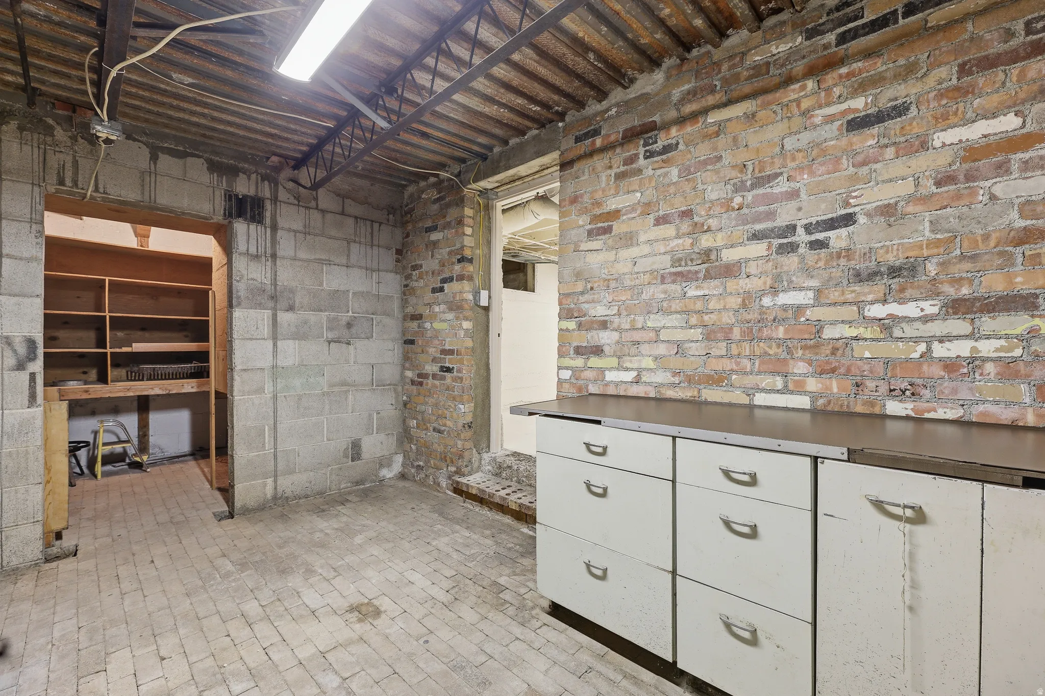 Exposed brick wall with built-in cabinetry and an industrial-style overhead light fixture
