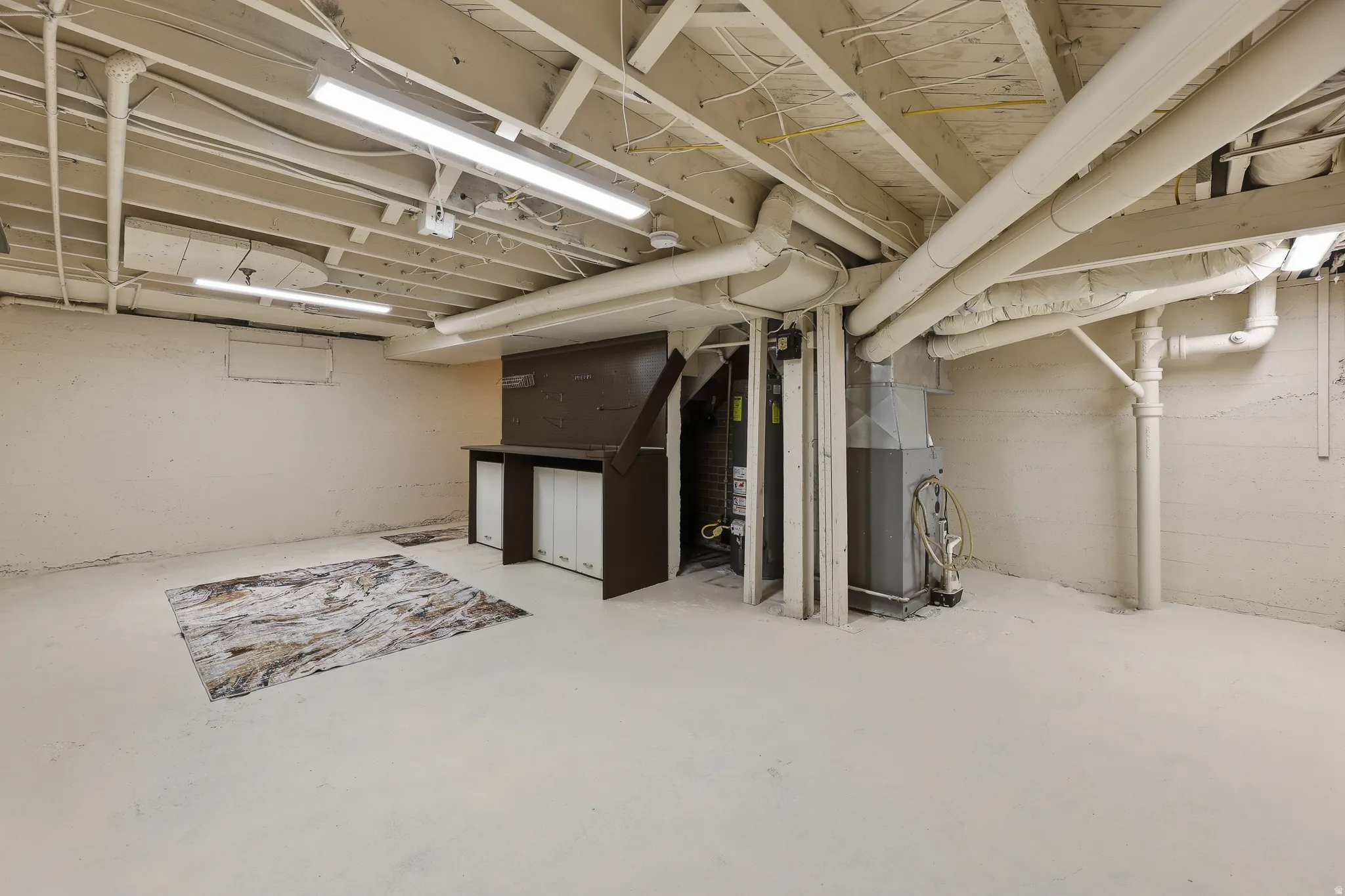 Unfinished basement offering exposed ceiling joists, concrete flooring, and multiple utility access points