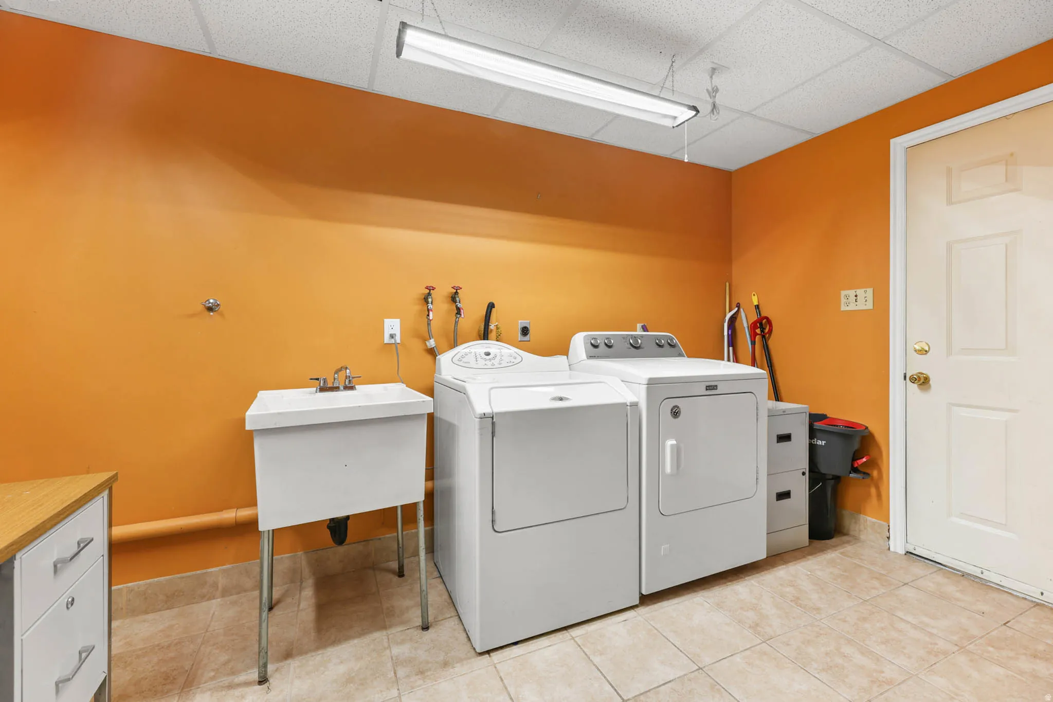 Laundry room featuring a drop ceiling, separate washer and dryer, and light tile patterned floors