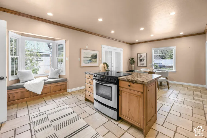 Kitchen with stainless steel electric range, a center island, recessed lighting, dark stone counters, and ornamental molding