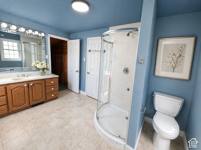 Full bath with vanity, a shower stall, and light tile patterned floors