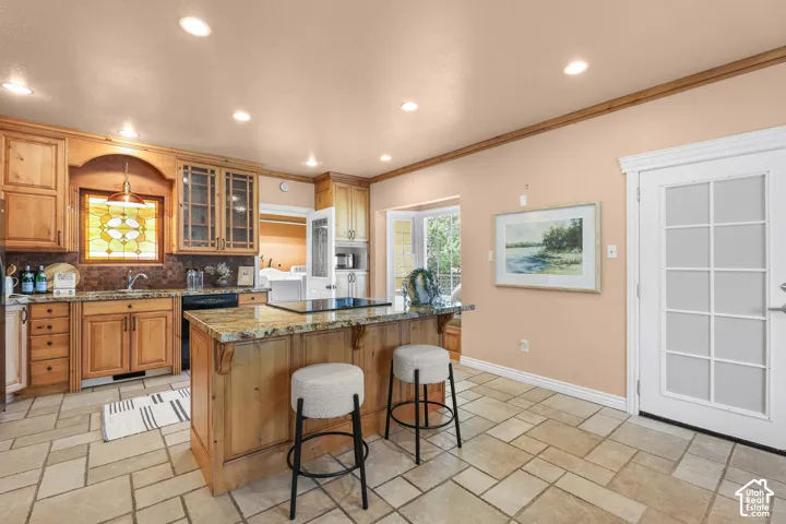 Kitchen with glass fronted cabinets, a breakfast bar area, dark stone countertops, recessed lighting, and a center island