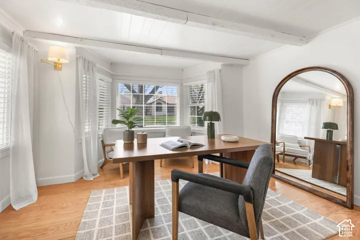 Dining space featuring beamed ceiling, light wood-type flooring, arched walkways, and crown molding