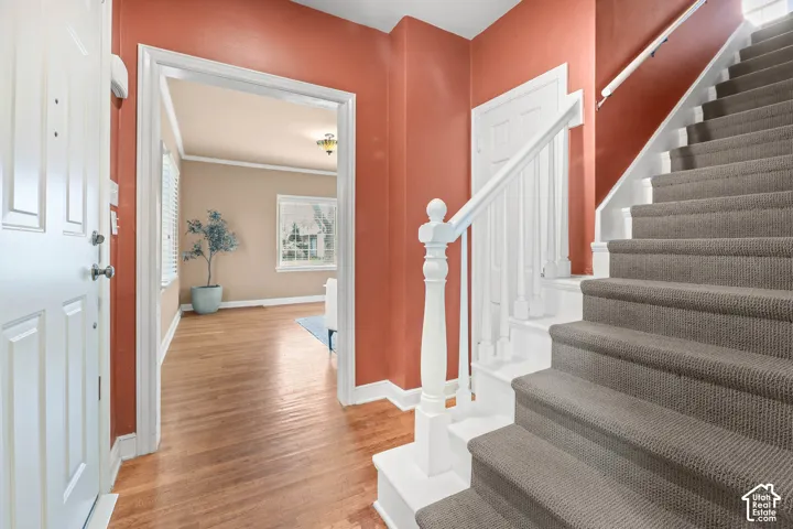 Foyer entrance with light wood-type flooring and ornamental molding