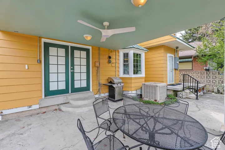 View of patio with outdoor dining space, grilling area, entry steps, french doors, and ceiling fan