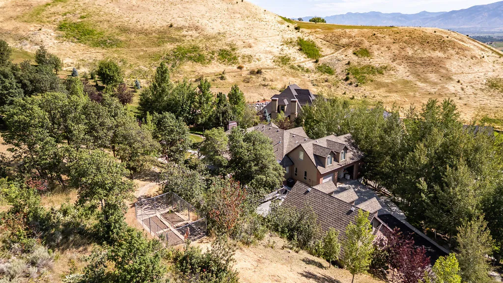 Expansive hillside property featuring a multi-level residence with dormer windows, a two-car garage, and a covered entryway