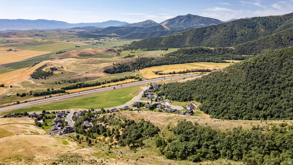 Expansive landscape featuring distant mountains, verdant hillsides, and a winding highway