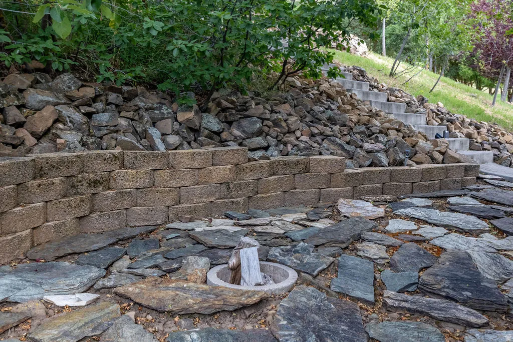 Terraced landscaping featuring a stacked stone retaining wall and an irregular flagstone patio