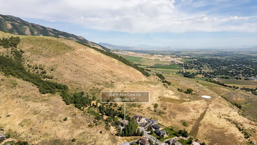 Elevated property location at the base of a verdant mountain range, featuring a residential community with mature trees