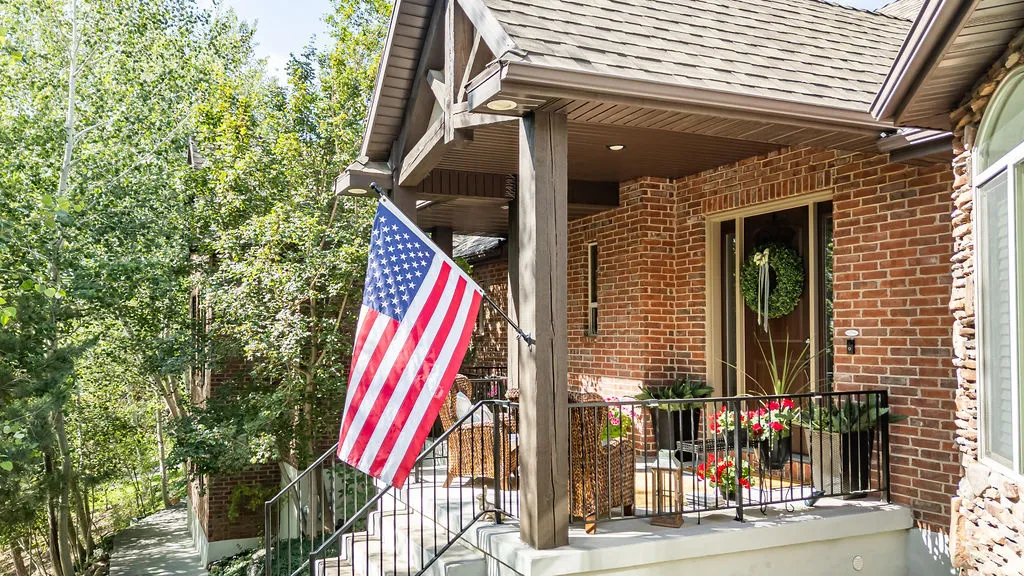 Brick exterior featuring a covered porch with a substantial wood column and dark metal railing