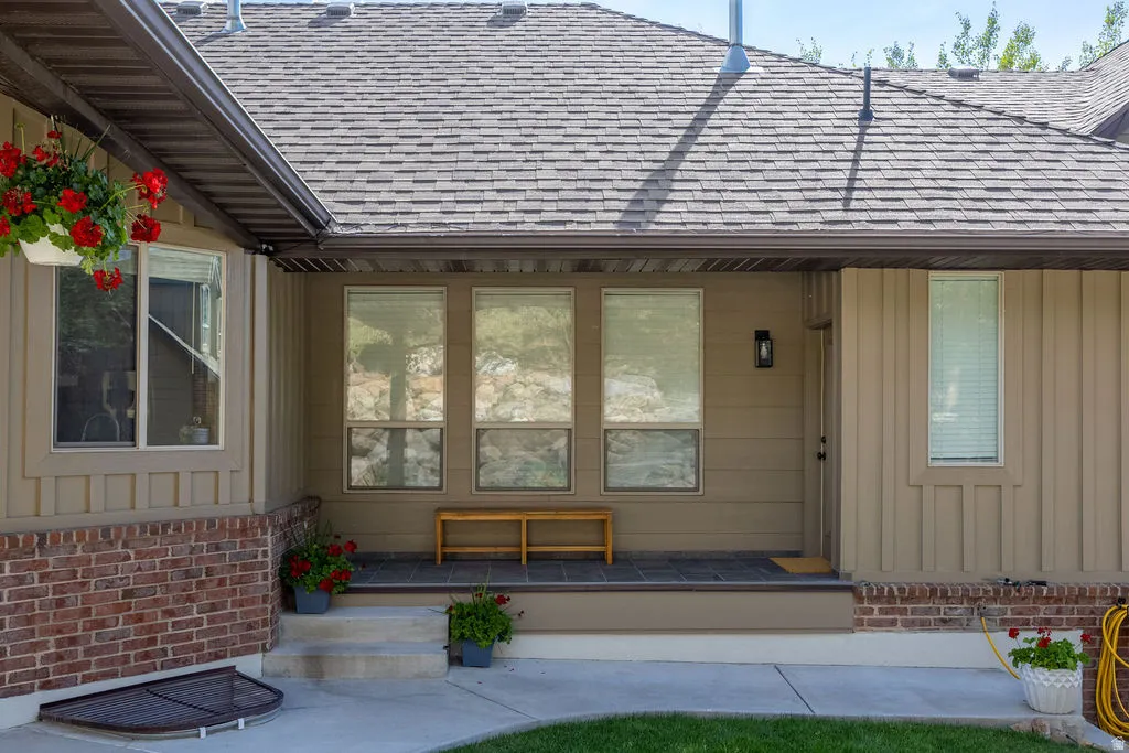 Covered porch entry featuring a rectangular exterior light fixture and multiple windows