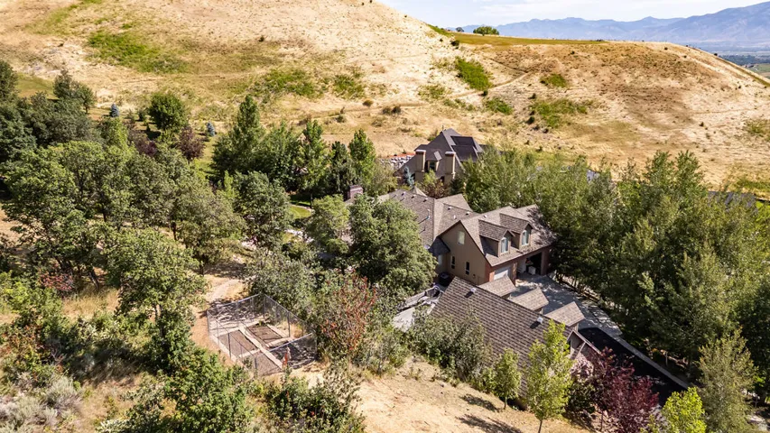 Expansive hillside property featuring a multi-level residence with dormer windows, a two-car garage, and a covered entryway