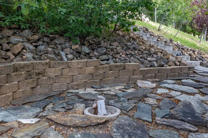 Terraced landscaping featuring a stacked stone retaining wall and an irregular flagstone patio
