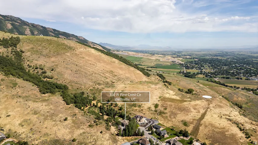 Elevated property location at the base of a verdant mountain range, featuring a residential community with mature trees