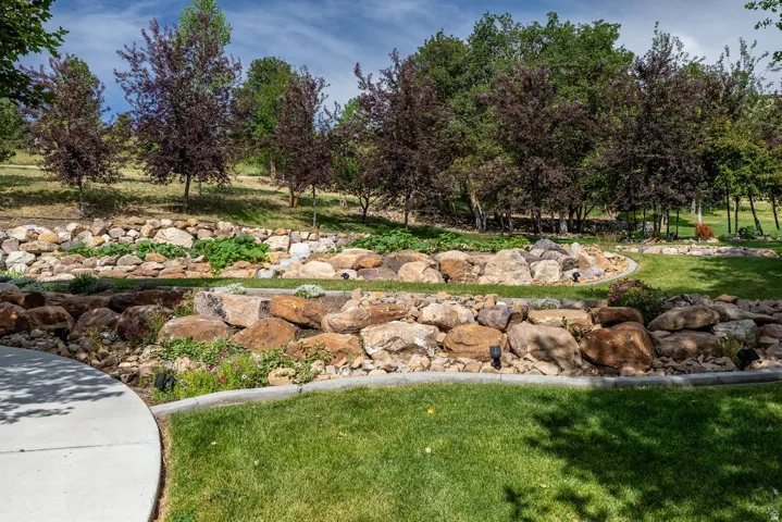 Tiered landscaping featuring natural rock walls, established shrubbery, and mature trees