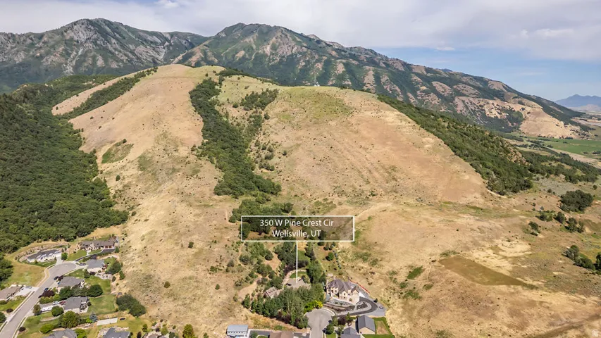 Aerial perspective showcasing a residential property nestled at the base of a significant mountain range