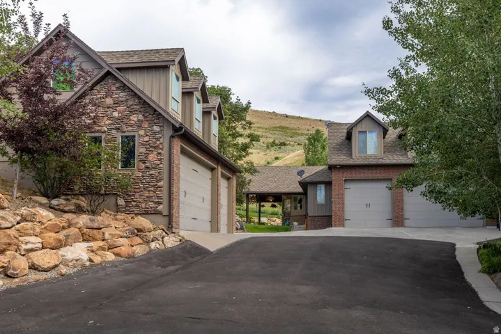 Multi-level residence featuring a stone and brick facade, gabled roofs, multiple dormer windows, and attached garages