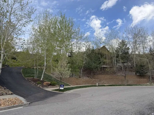 Hillside property featuring a multi-level house, a winding asphalt driveway, and a retaining wall