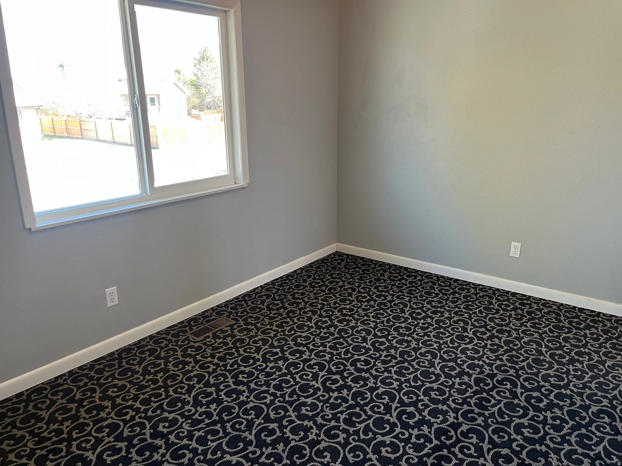 Empty room with baseboards and dark carpet