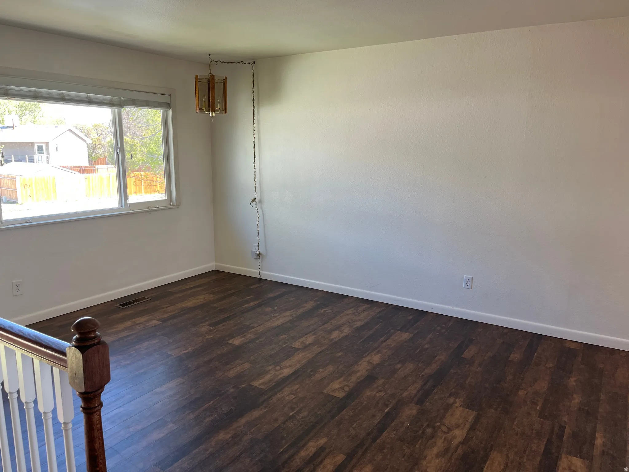 Spare room featuring dark wood-style floors and baseboards