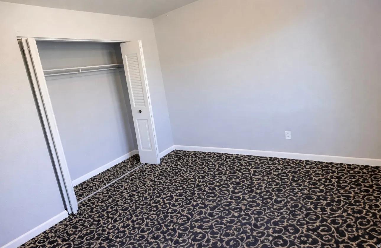 Unfurnished bedroom featuring a closet and dark carpet