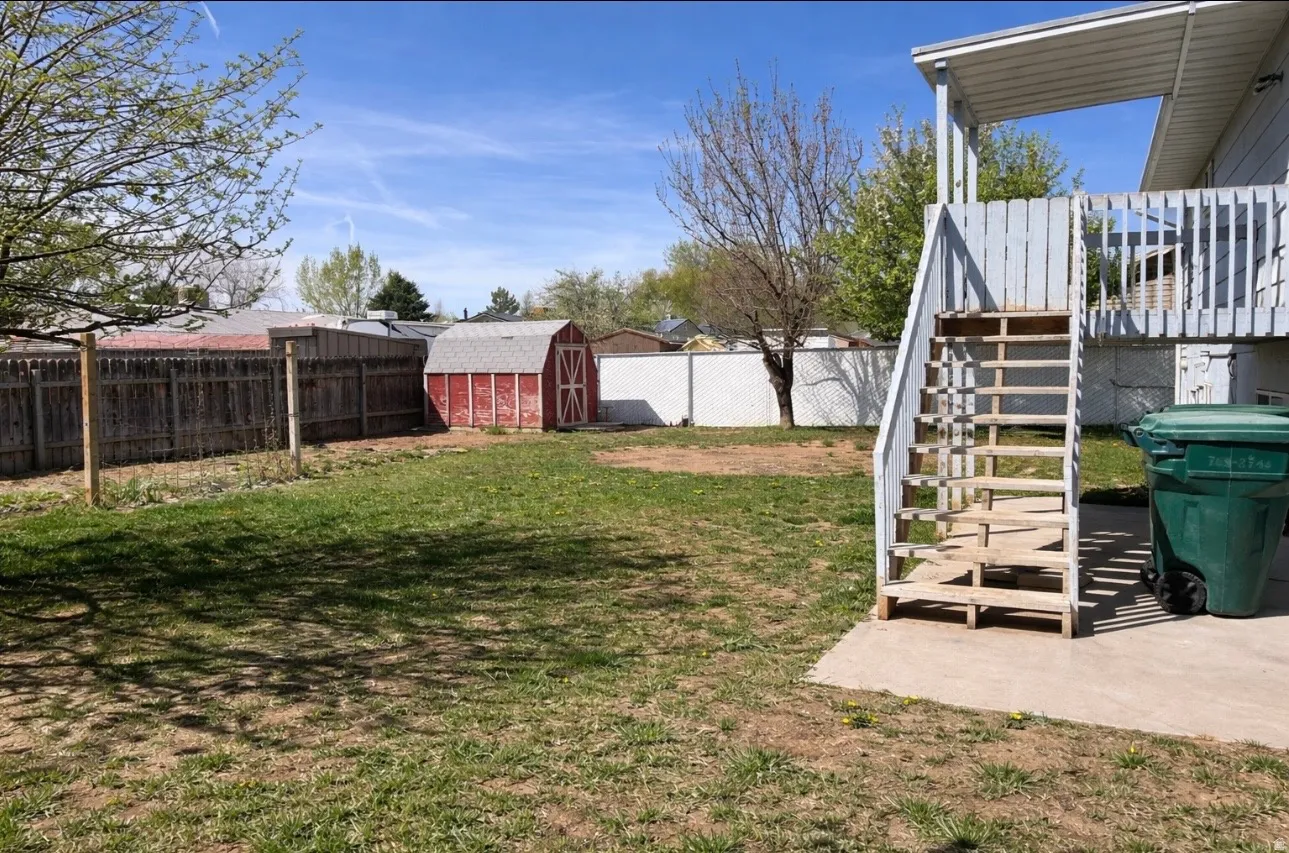 Fenced backyard featuring a patio area and a storage shed