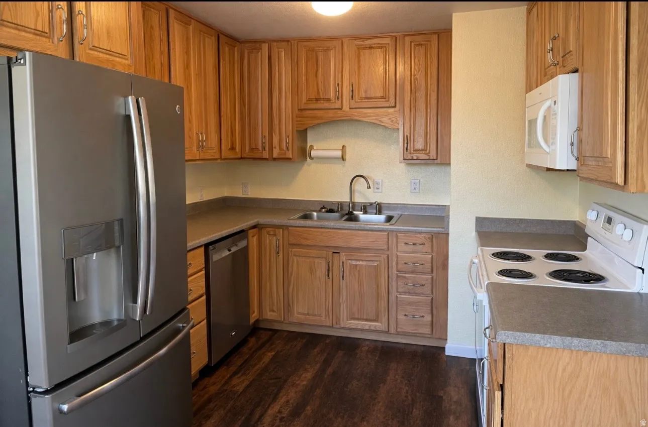 Kitchen with stainless steel appliances, wood finish cabinets, dark wood finished floors, and light countertops